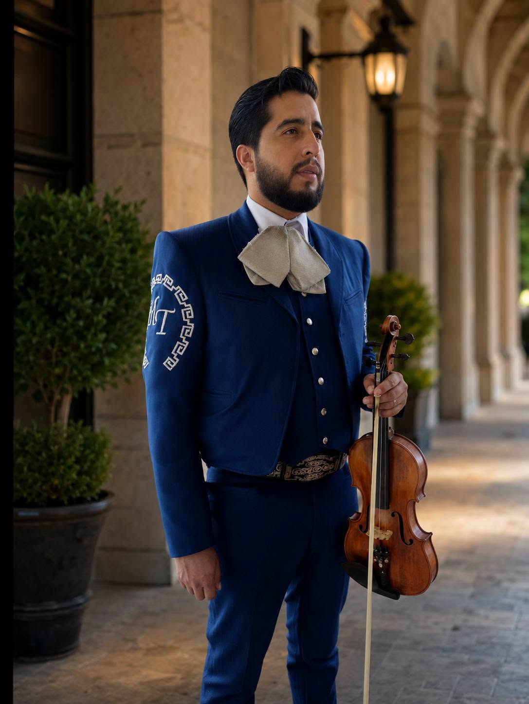 Violinista del mariachi con traje charro azul en un pasillo de columnas